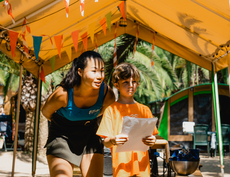 Een activiteitenbegeleider van Estivant samen met een kind in de zomer