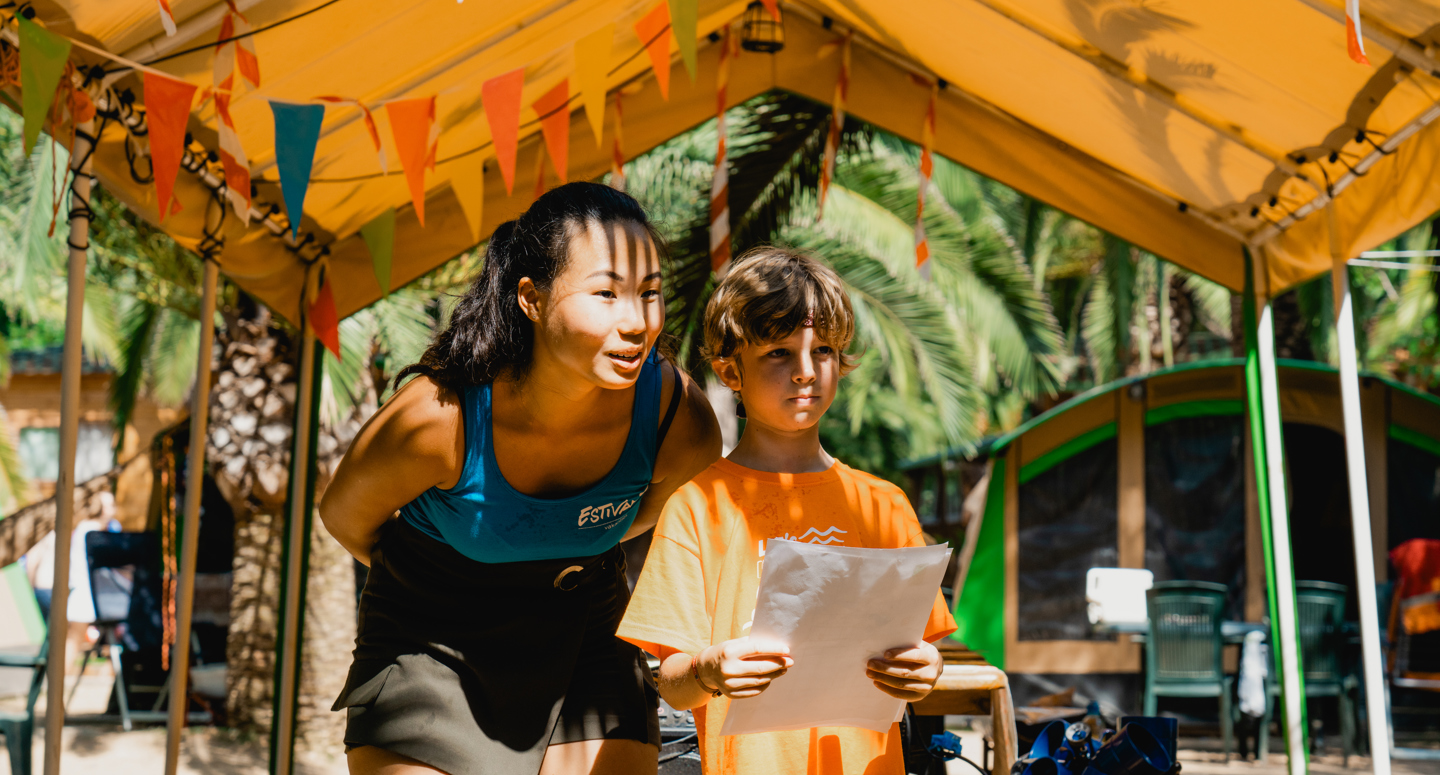 Een activiteitenbegeleider van Estivant samen met een kind in de zomer