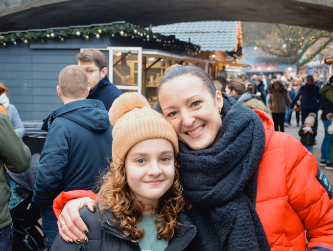 Een moeder samen met haar dochter op een kerstmarkt
