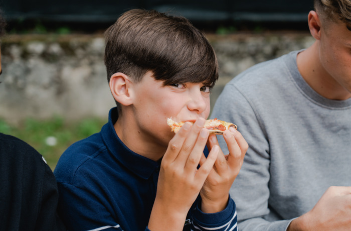 Een jongen smult van zijn pizza 