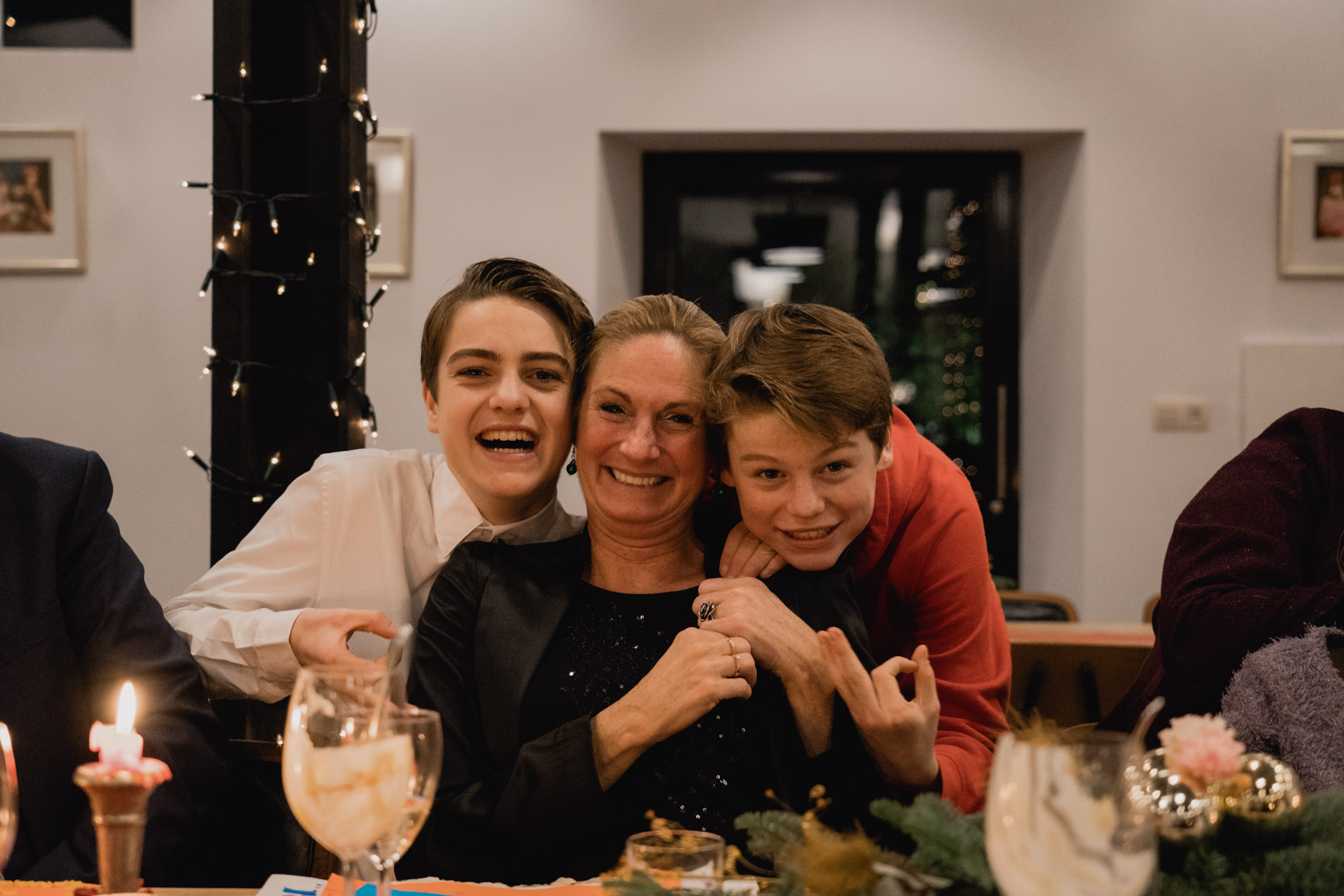 Moeder poseert lachend met haar zoons tijdens een kerstdiner