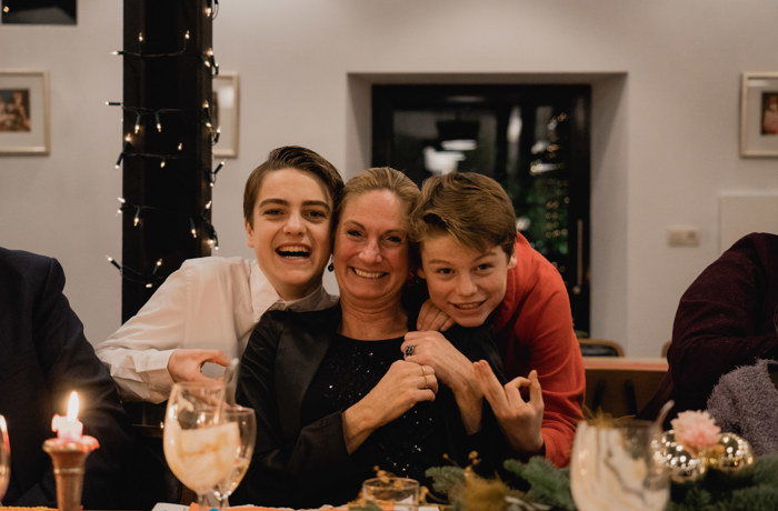 Moeder poseert lachend met haar zoons tijdens een kerstdiner