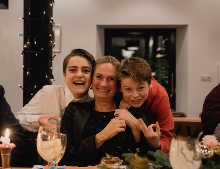 Moeder poseert lachend met haar zoons tijdens een kerstdiner