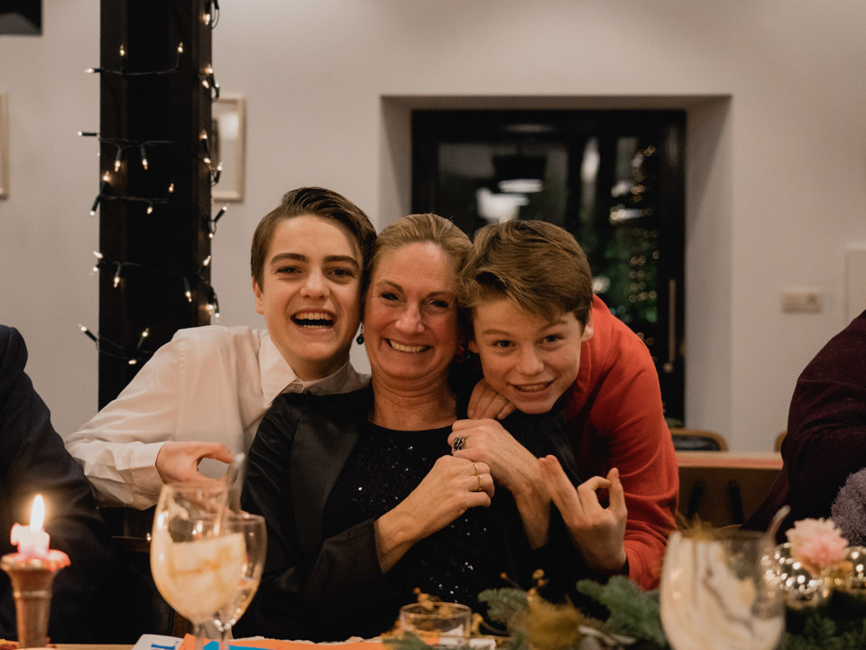 Moeder poseert lachend met haar zoons tijdens een kerstdiner