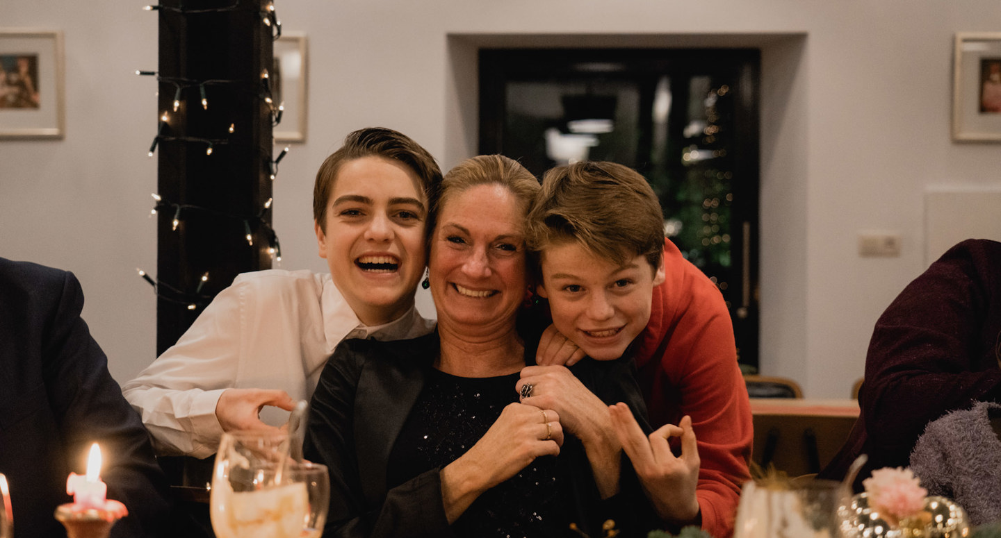 Moeder poseert lachend met haar zoons tijdens een kerstdiner