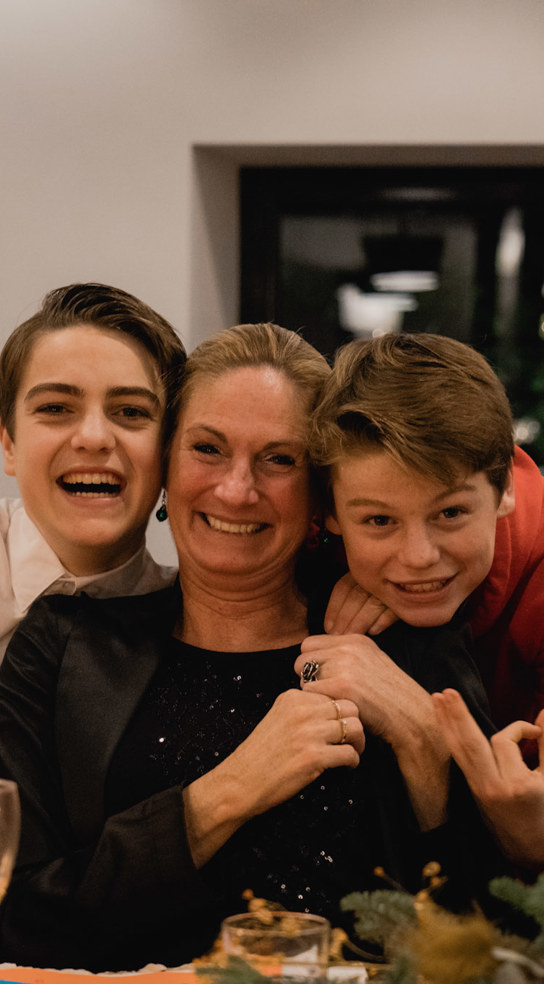 Moeder poseert lachend met haar zoons tijdens een kerstdiner