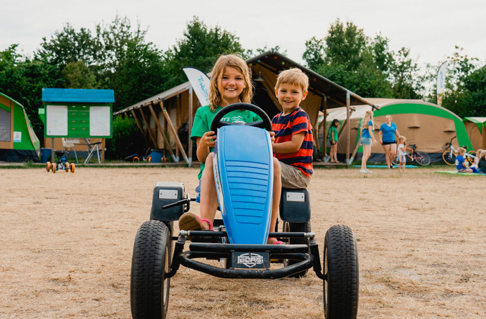 2 kinderen rijden in een skelter op de camping