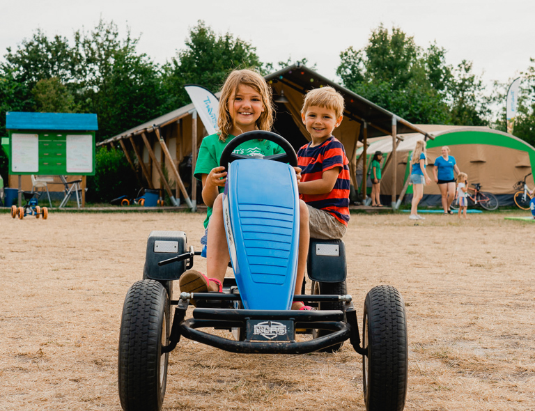 2 kinderen rijden in een skelter op de camping