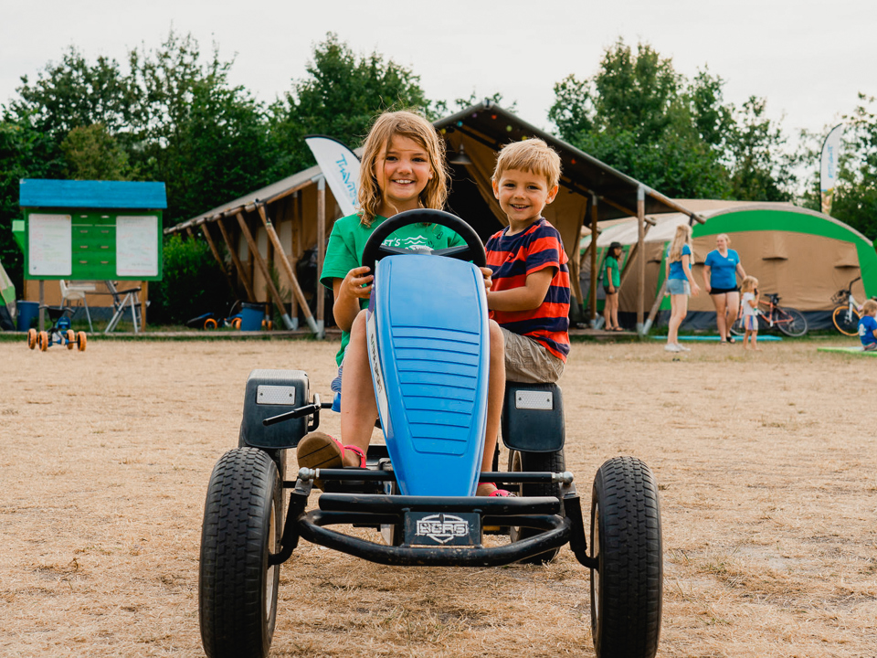 2 kinderen rijden in een skelter op de camping