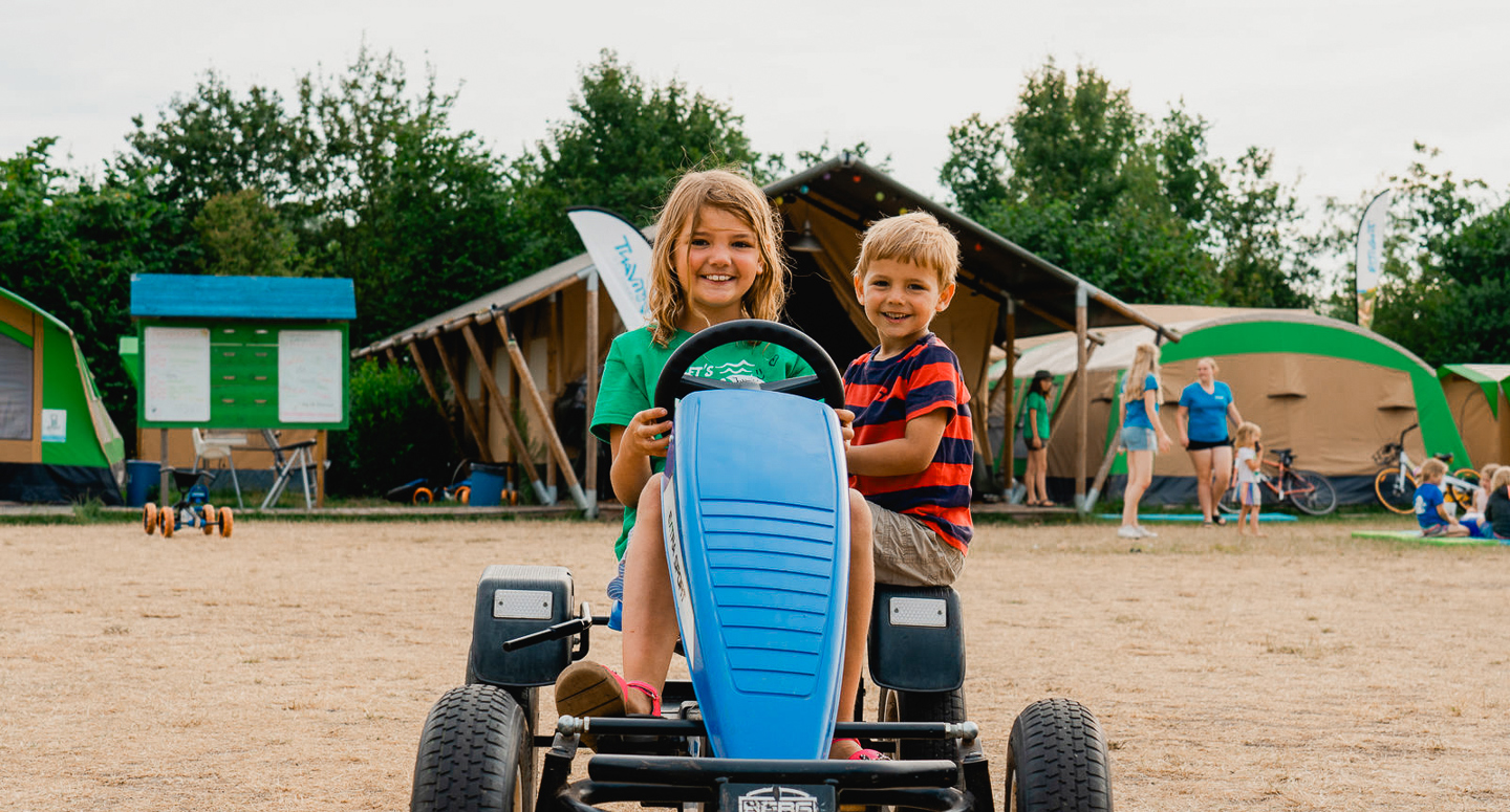 2 kinderen rijden in een skelter op de camping