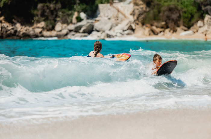 Kinderen surfen door kraakheldere golven