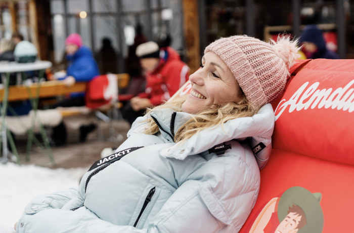 Vrouw geniet op haar ligstoel bij een Oostenrijkse skihut