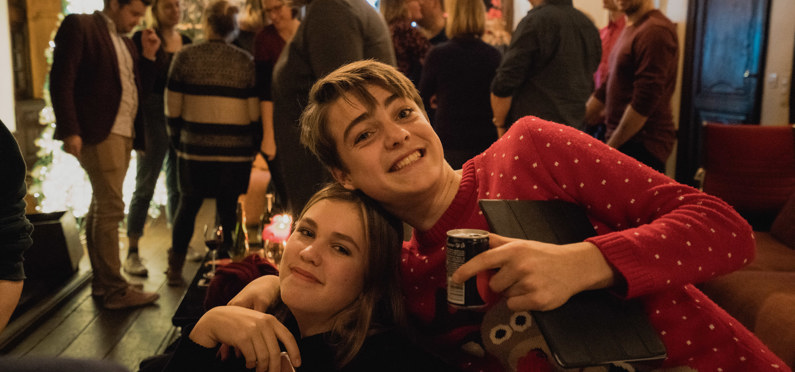 Twee kinderen poseren tijdens kerst voor een foto met ouders op de achtergrond